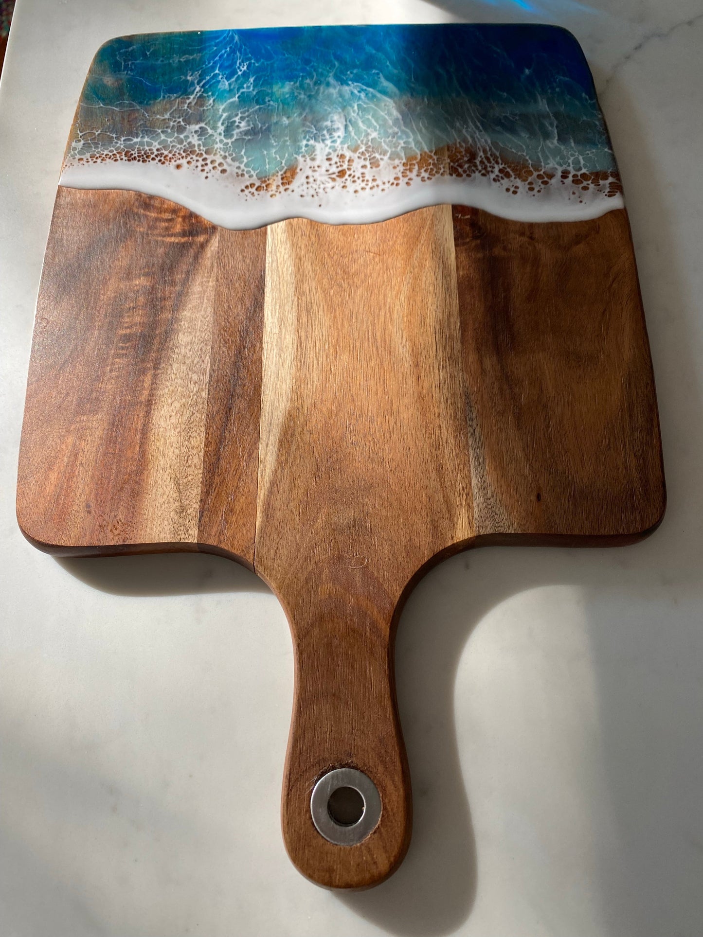 Acacia wood paddle board wth triple blue ocean waves.