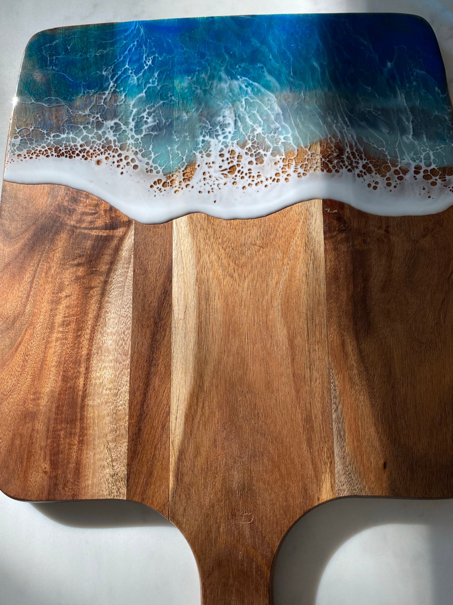 Acacia wood paddle board wth triple blue ocean waves.