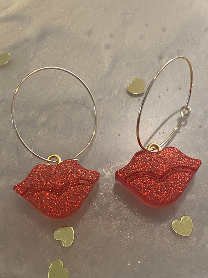 Sparkly resin lip 👄 earrings dangling from 14k gold plated hoops or danglers.