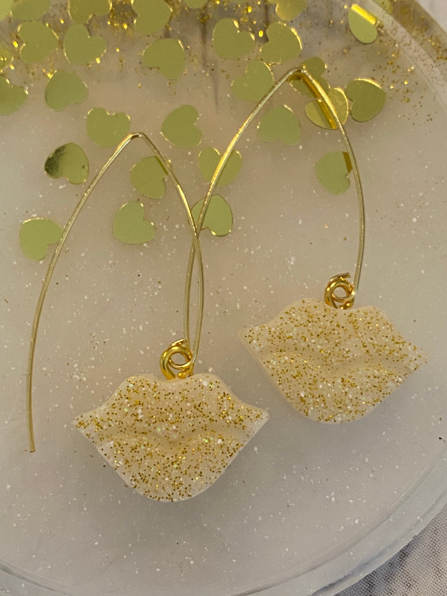 Sparkly resin lip 👄 earrings dangling from 14k gold plated hoops or danglers.